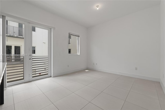unfurnished room featuring baseboards, light tile patterned flooring, and french doors