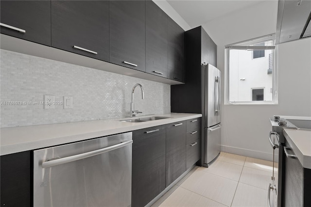 kitchen with light countertops, modern cabinets, a sink, tasteful backsplash, and appliances with stainless steel finishes