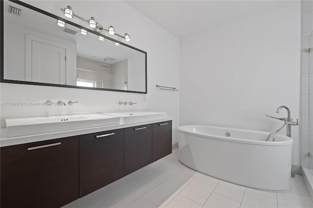 full bath with tile patterned floors, a sink, double vanity, and a freestanding bath