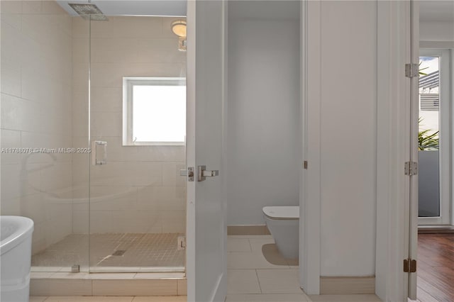 full bath featuring plenty of natural light, a shower stall, tile patterned floors, and toilet
