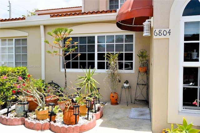property entrance with a tile roof and stucco siding