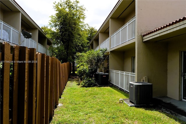 view of yard featuring fence and central AC