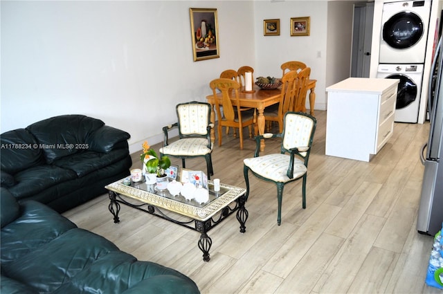 living area featuring stacked washer / dryer, light wood-style flooring, and baseboards