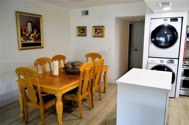 dining room with stacked washer / drying machine, visible vents, and light wood-style floors