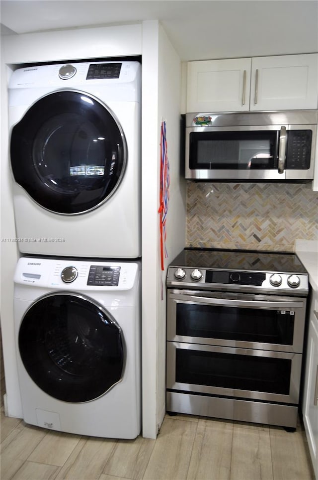 laundry area with stacked washer and dryer, light wood-style flooring, and laundry area