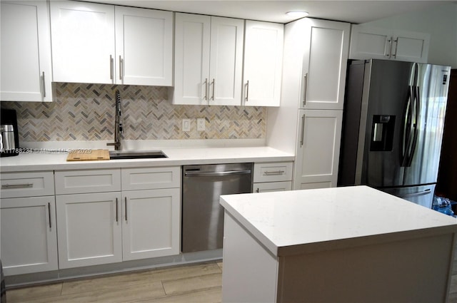 kitchen featuring a sink, backsplash, stainless steel appliances, and white cabinetry