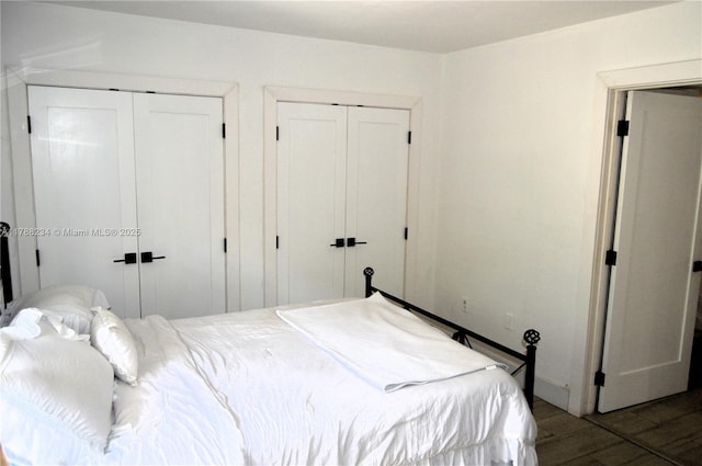 bedroom with two closets, wood finished floors, and baseboards