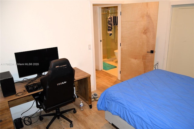 bedroom featuring wood finished floors and ensuite bathroom