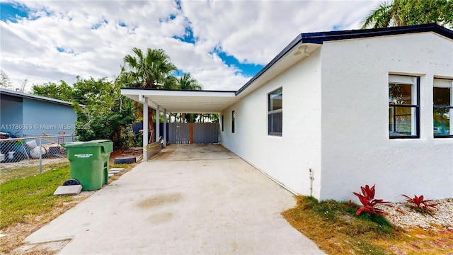 1550 NE 11th St, Homestead, FL 33033 - view of side of home featuring stucco siding, an attached carport, and concrete driveway