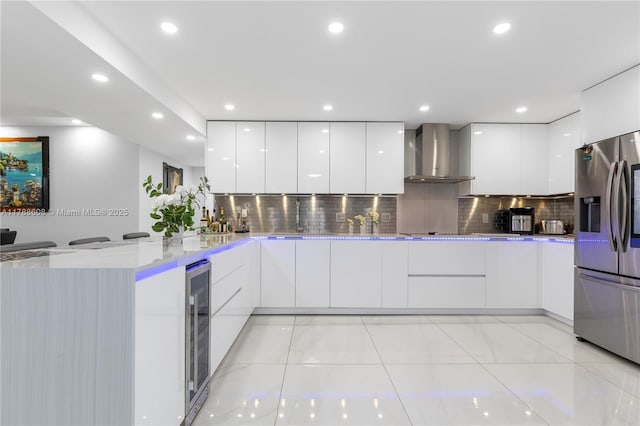 2500 Parkview Dr Unit 1121, Hallandale Beach, FL 33009 - kitchen featuring a peninsula, white cabinetry, modern cabinets, wall chimney range hood, and stainless steel fridge with ice dispenser