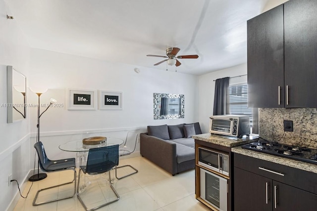 335 Ocean Dr Unit 310, Miami Beach, FL 33139 - kitchen featuring black gas cooktop, a toaster, stainless steel microwave, decorative backsplash, and a ceiling fan