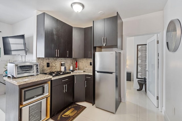 335 Ocean Dr Unit 310, Miami Beach, FL 33139 - kitchen with a sink, light tile patterned floors, a toaster, stainless steel appliances, and backsplash