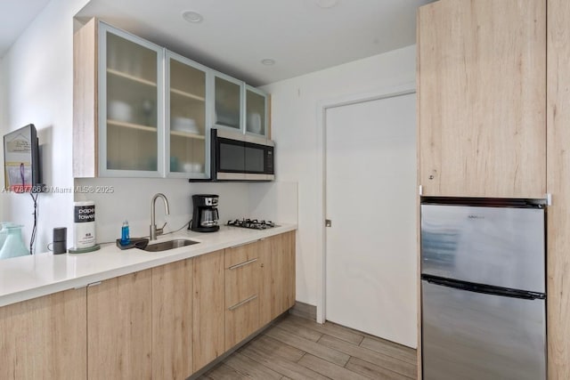 335 Ocean Dr Unit 122, Miami Beach, FL 33139 - kitchen with light brown cabinetry, a sink, light wood-style floors, modern cabinets, and appliances with stainless steel finishes