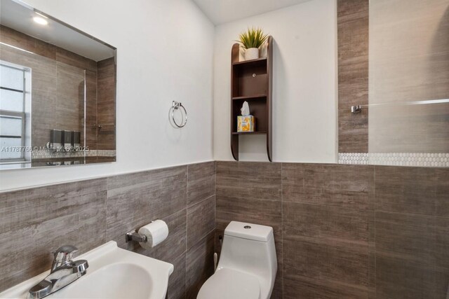 335 Ocean Dr Unit 122, Miami Beach, FL 33139 - bathroom with toilet, a wainscoted wall, a sink, and tile walls