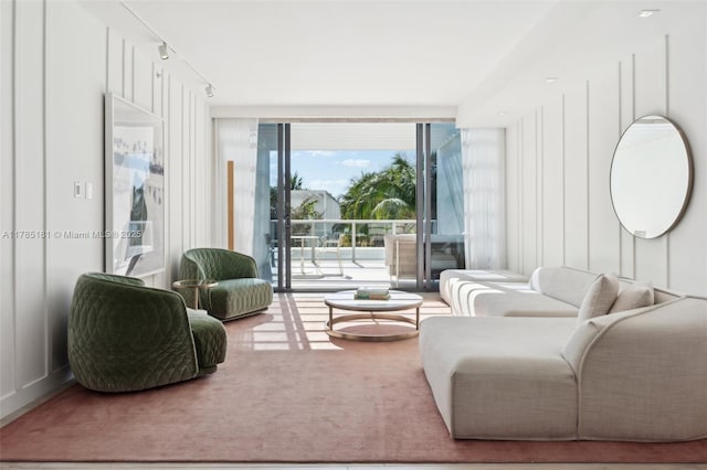 carpeted living room with track lighting and a wall of windows
