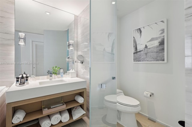 bathroom featuring baseboards, toilet, and vanity