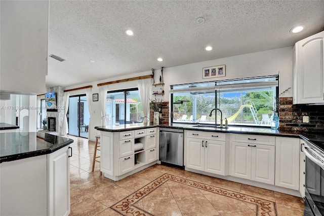 kitchen featuring a sink, a textured ceiling, appliances with stainless steel finishes, a peninsula, and white cabinetry