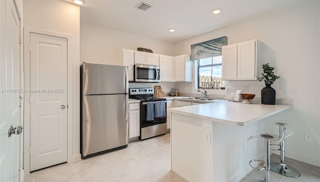 1472 NE 3rd Ave, Florida City, FL 33034 - kitchen with a kitchen breakfast bar, a sink, a peninsula, appliances with stainless steel finishes, and white cabinetry