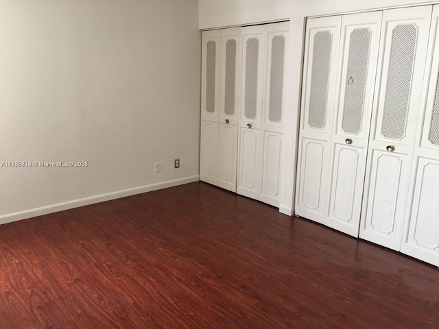 16909 N Bay Rd Unit 211, Sunny Isles Beach, FL 33160 - unfurnished bedroom with two closets, baseboards, and dark wood-style flooring