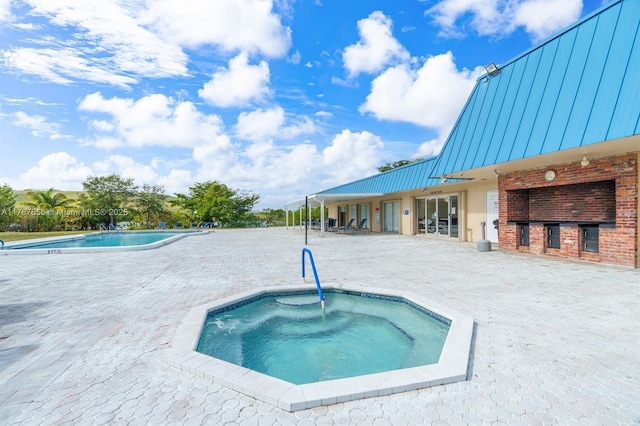 pool with a patio area and a hot tub