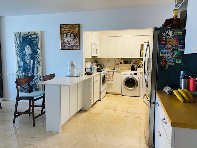 770 NE 69th St Unit 4B, Miami, FL 33138 - kitchen with washer / clothes dryer, white appliances, a peninsula, a sink, and white cabinetry