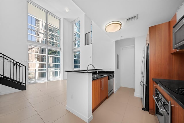 300 S Biscayne Blvd Unit L-802, Miami, FL 33131 - kitchen featuring appliances with stainless steel finishes, brown cabinetry, dark countertops, and modern cabinets