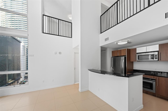 300 S Biscayne Blvd Unit L-802, Miami, FL 33131 - kitchen with appliances with stainless steel finishes, dark countertops, a high ceiling, a peninsula, and baseboards