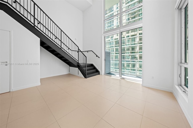300 S Biscayne Blvd Unit L-802, Miami, FL 33131 - unfurnished living room with a high ceiling, healthy amount of natural light, stairs, baseboards, and tile patterned floors