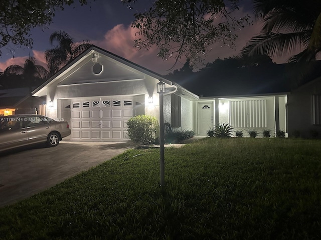 ranch-style house featuring a garage, driveway, a front yard, and stucco siding