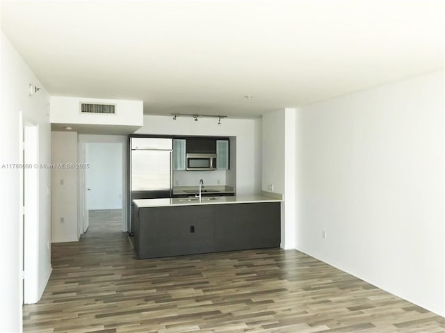 kitchen featuring wood finished floors, visible vents, a sink, a peninsula, and appliances with stainless steel finishes