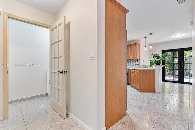 hallway featuring a sink, light tile patterned floors, french doors, baseboards, and visible vents
