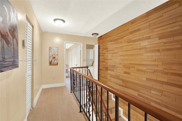 3904 Estepona Ave Unit 8D2, Doral, FL 33178 - hallway featuring an upstairs landing, a textured ceiling, wood walls, light wood finished floors, and baseboards