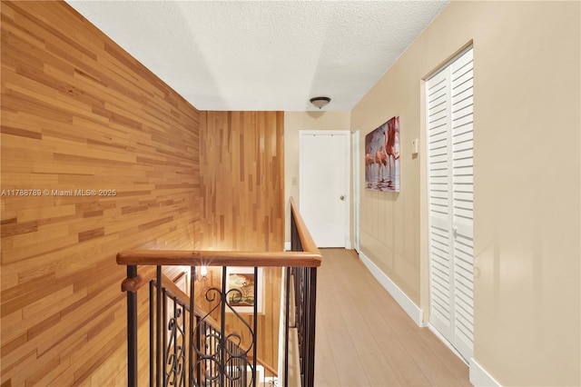3904 Estepona Ave Unit 8D2, Doral, FL 33178 - hallway featuring an upstairs landing, wooden walls, a textured ceiling, wood finished floors, and baseboards