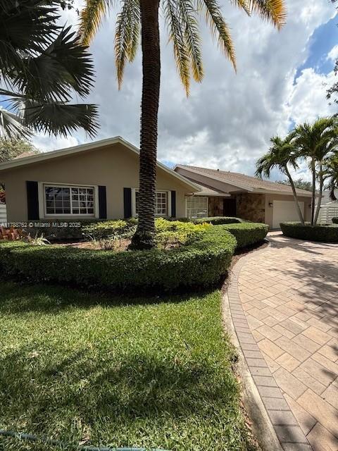 15242 SW 147th Ter, Miami, FL 33196 - view of property exterior with stucco siding, a garage, and a lawn