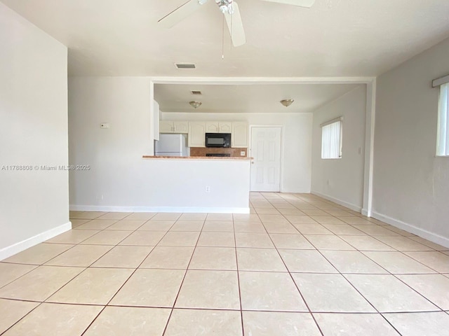 unfurnished living room with baseboards, visible vents, ceiling fan, and light tile patterned flooring