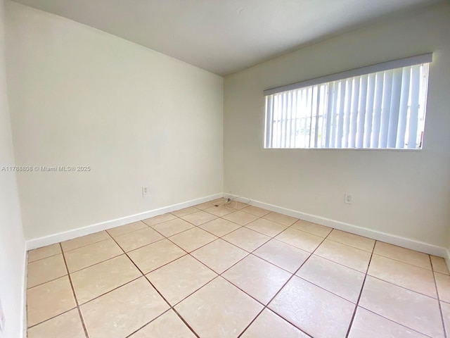 empty room with baseboards and light tile patterned flooring