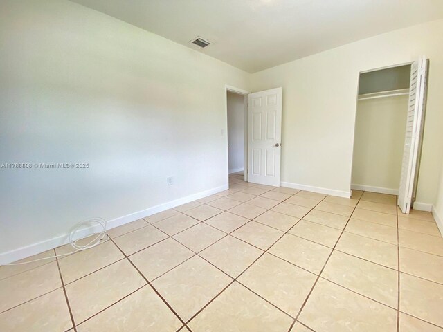 unfurnished bedroom featuring baseboards, a closet, visible vents, and light tile patterned floors