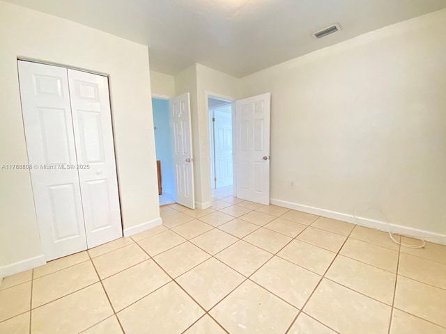 unfurnished bedroom with baseboards, a closet, visible vents, and light tile patterned floors