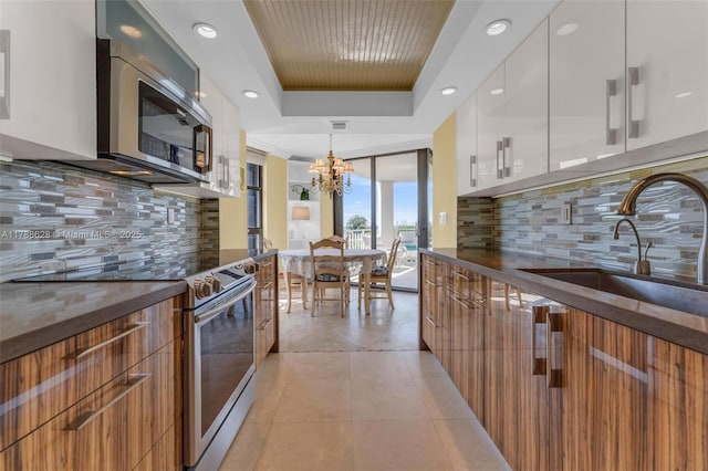 2000 Towerside Ter Unit 702, Miami, FL 33138 - kitchen featuring a notable chandelier, a sink, a raised ceiling, stainless steel appliances, and modern cabinets