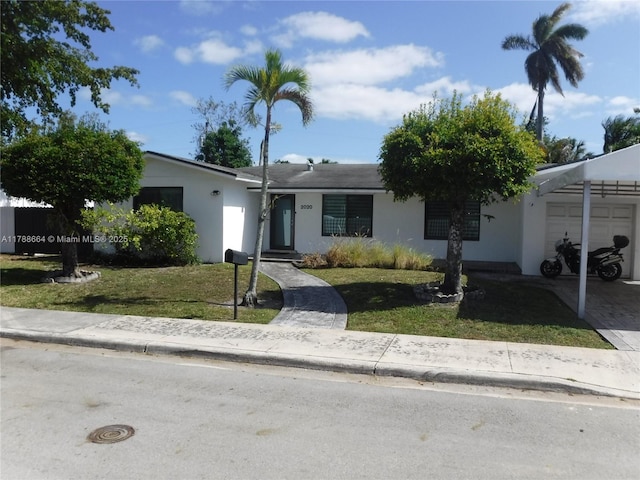 ranch-style house with a garage, stucco siding, driveway, and a front yard