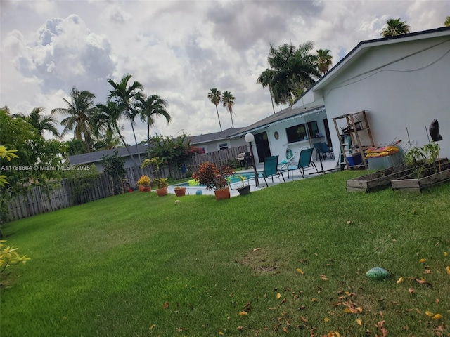 view of yard with a fenced in pool, fence, a vegetable garden, and a patio