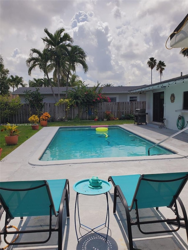 view of swimming pool featuring a patio, a fenced in pool, a fenced backyard, and a grill
