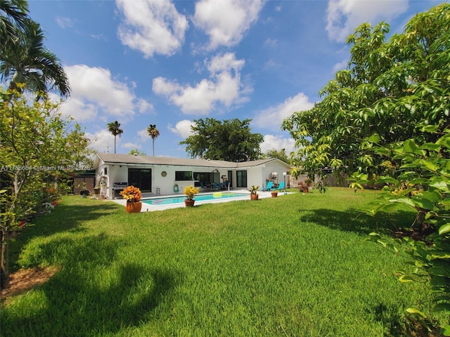 back of house with fence, stucco siding, a yard, and an outdoor pool