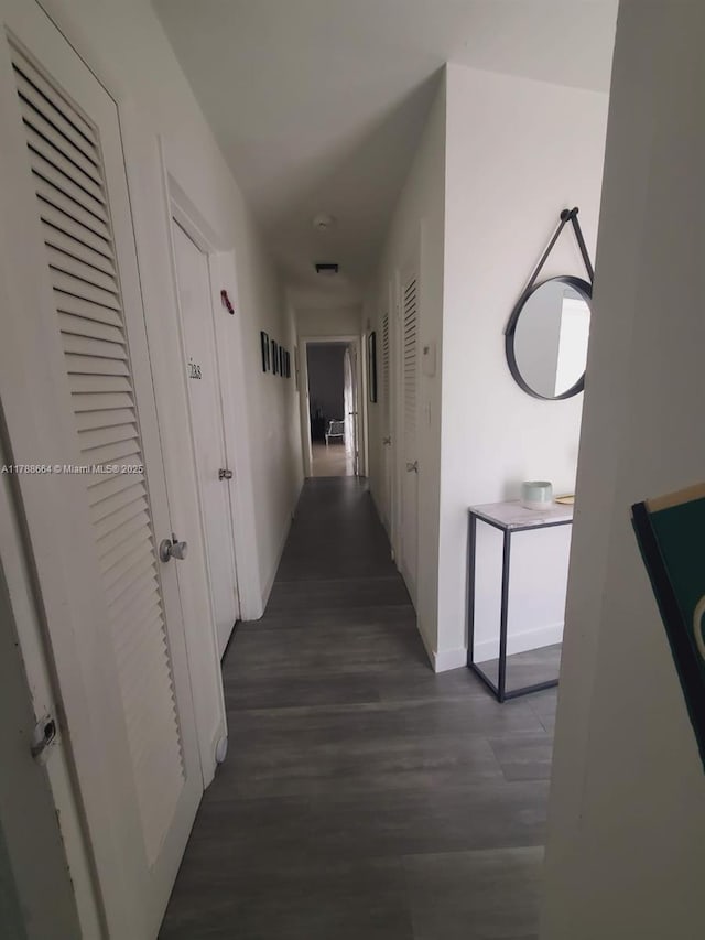 corridor with baseboards and wood finished floors