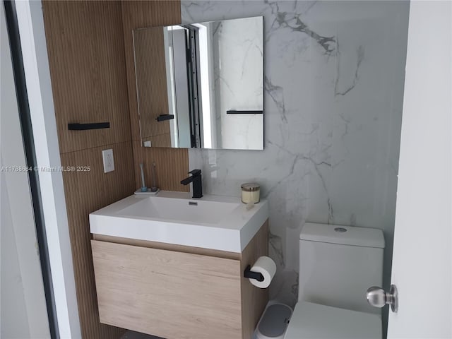 bathroom with tile walls, vanity, and toilet