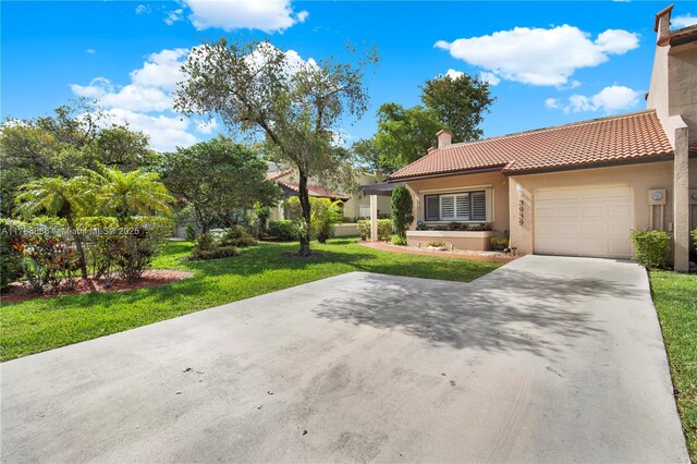 3939 Adra Ave Unit A-47, Doral, FL 33178 - view of front facade with a chimney, a tiled roof, a front lawn, stucco siding, and an attached garage