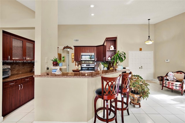 3939 Adra Ave Unit A-47, Doral, FL 33178 - kitchen featuring stainless steel appliances, high vaulted ceiling, backsplash, and light tile patterned floors
