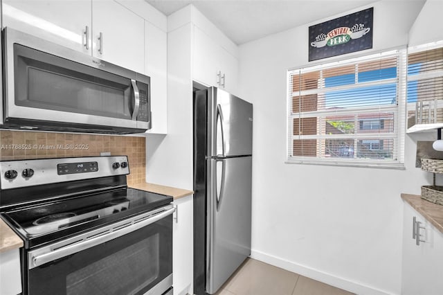 kitchen featuring decorative backsplash, light tile patterned flooring, stainless steel appliances, light countertops, and white cabinets