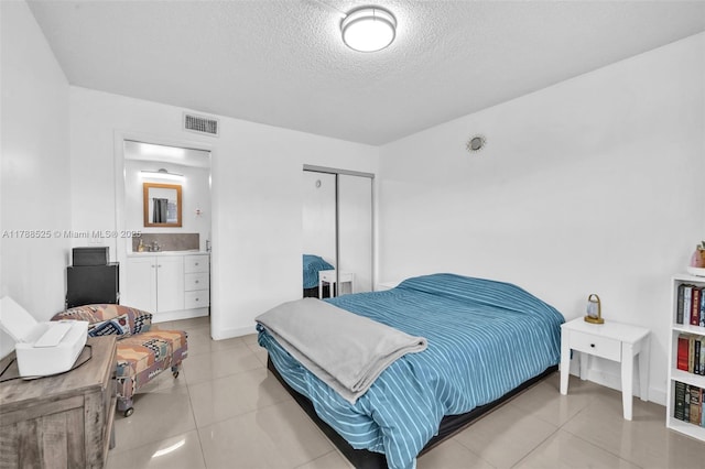 tiled bedroom with a closet, a textured ceiling, and visible vents