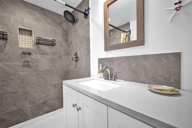 full bath featuring decorative backsplash, vanity, and tiled shower